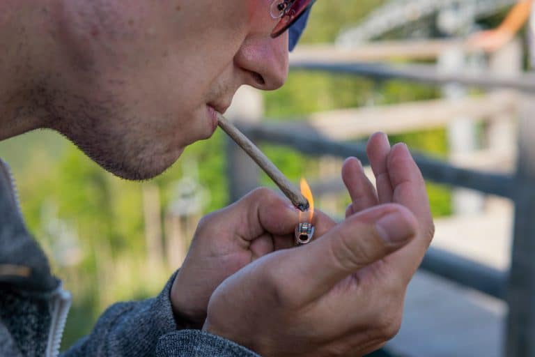 close up de jovem fumando charro de maconha ao ar livre