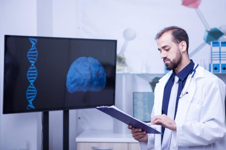 confiante jovem medico com uma prancheta nas maos ao lado de um monitor com um grafico cerebral belo medico