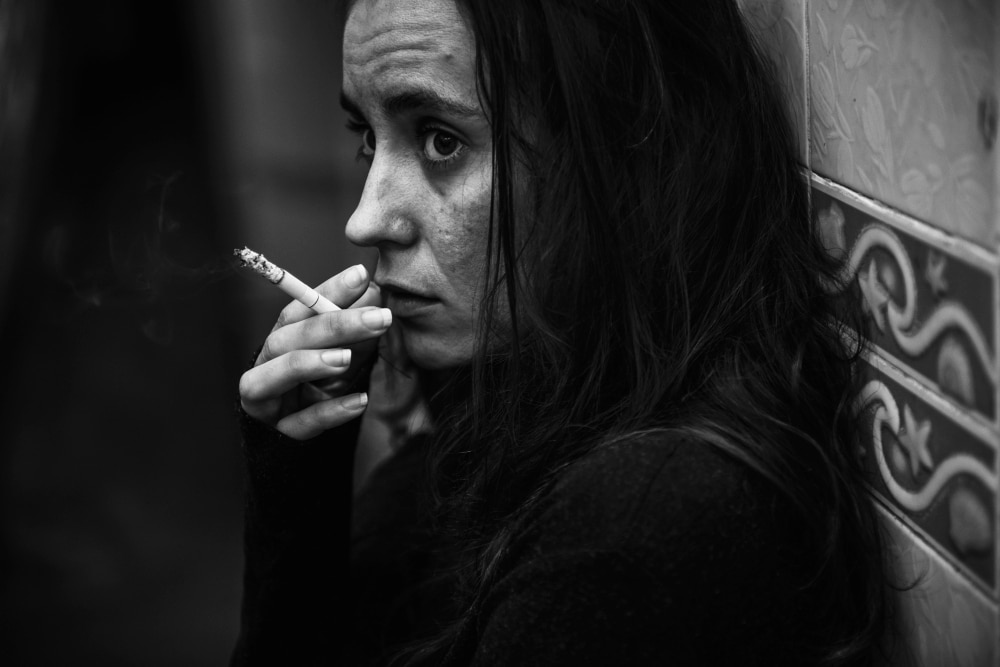 mulher fumando cigarro sozinho em tons de cinza