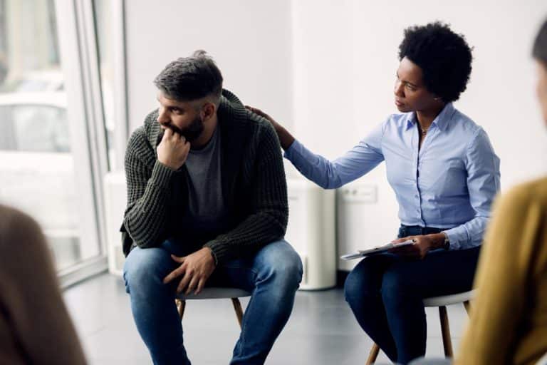 terapeuta negra apoiando um homem que esta falando sobre seus problemas durante a reuniao do grupo